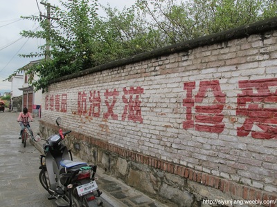 A bicycle and motorcycle beside a wall painted with Chinese characters